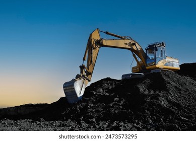 Coal mining in an open pit. Mining excavator loads coal in haul truck in quarry. Excavator digging in open pit coal mine. Excavator in open-pit on sunset background. Heavy machinery in opencast. 