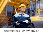 Coal mining worker use tablet computer on background big yellow truck.