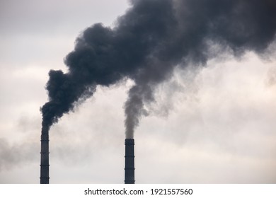 Coal power plant high pipes with black smoke moving up polluting atmosphere.