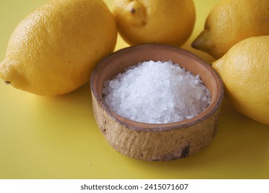 Coarse salt in a bowl and lemon on yellow background  - Powered by Shutterstock