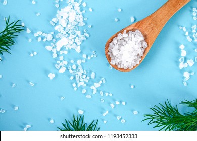 Coarse salt crystals on a blue table. Wooden spoon with sea salt. Background for advertising salty.