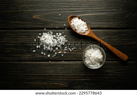 Coarse sea salt in a wooden spoon and on a vintage table. Traditional medicine concept