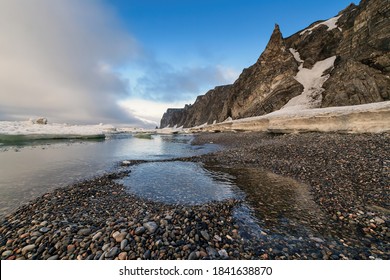 Coast of the Arctic Ocean near the Bering Strait. Cold summer in the Arctic. Melting ice at the end of June on the coast of the Arctic Ocean. Cape Uelen, Chukchi Peninsula, Chukotka, Far East Russia.