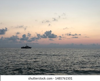 Coast Guard Ship Silhouette At Sunset. Border Boat With Weapons And Military On Board. Silhouette Of A Warship In The Background The Evening Sky At Sunset.