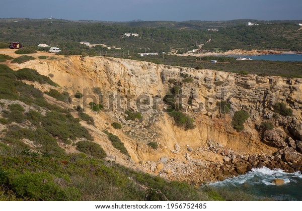 coastal camper and car\
parking lot at rugged and eroded steep cliff coastline seen from\
the top of the cliff overlooking the coastal nature trail along the\
rocky coast