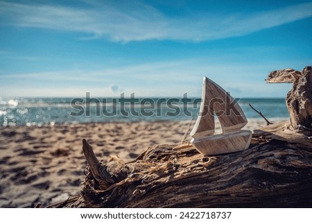 Coastal Dreams - Wooden sailboat model on a sunlit beach, capturing the essence of seaside nostalgia.