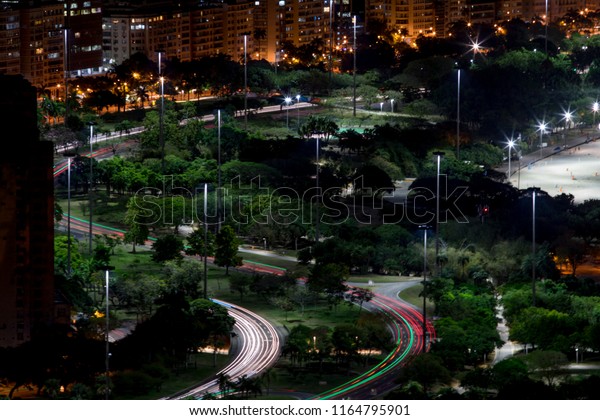 Coastal highways with car\
lights through Rio de Janeiro at night with the Flamengo beach in\
the background and a monument in the foreground on a long exposure\
at night