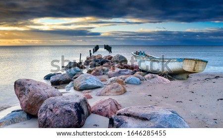 Coastal landscape with a broken old pier and fishing boat after storm, former areas of cooperative fisheries on the Baltic Sea