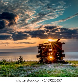 Coastal landscape on a beach of the Baltic Sea in Jurmala, Latvia. Wooden log deck for a fire that will be used as a symbol of traditional Latvian holiday of summer solstice - Ligo