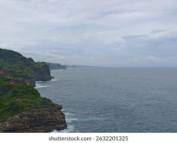 Coastal landscape view showing a dramatic cliffside meeting a wide expanse of ocean. The scene is overcast, with muted colors and a sense of quiet serenity.  - Powered by Shutterstock - Get 15% off with code: PIKWIZARD15