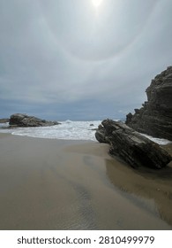 Coastal rock formations under dramatic sun halo sky