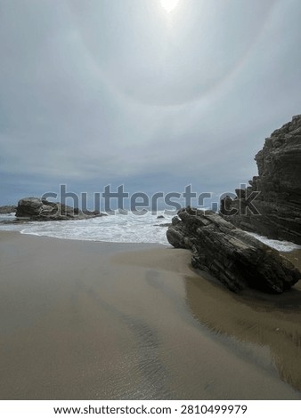 Coastal rock formations under dramatic sun halo sky