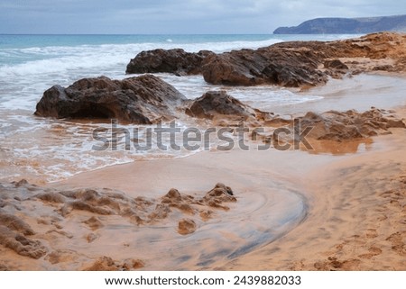 Coastal rocks and shore water. Beach landscape of Porto Santo island on a cloudy stormy day. Madeira archipelago, Portugal