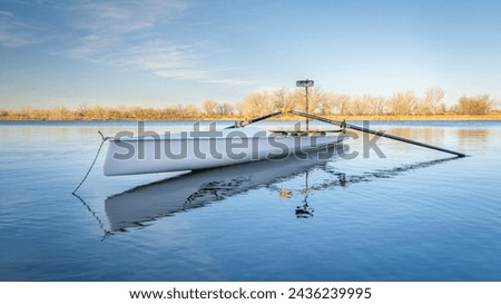 Coastal rowing shell by on a lake in northern Colorado in winter or early spring scenery.