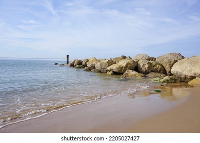 Coastal Sea Defence Made From Large Boulder Rocks. Sandy Beach In Dorset UK. Peaceful Empty Beach View Looking Out To The Sea. 