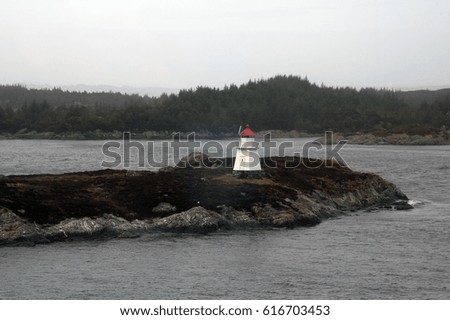 Coastline Norway, remote island lighthouse with forested coastline in background