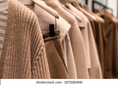 Le manteau et le chandail brun clair sur le cintre dans le magasin. Des vêtements de mode féminins classiques.