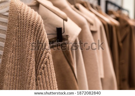Coat and sweater light brown on the hanger in the store. Classic women's fashion clothes.