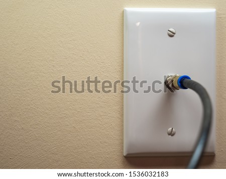 Coax cable cord connected to wall outlet. Coaxial wire connection for TV and high speed broadband internet. Television service installation.
