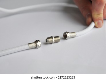 Coaxial cables connection, TV cable connector.Repairman connecting two coaxial TV cables.