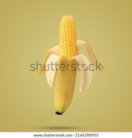 Cob of corn in the peel of banana on yellow background. Fruit concept. Food creative concept. Photo manipulation with banana. Art concept.