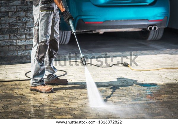 Cobble\
Driveway Pressure Washing by Caucasian\
Worker.