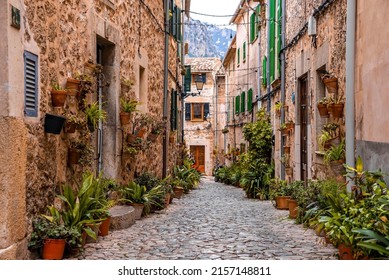 Cobbled street alley with potted plants. Decorated old buildings in town at residential district. Concept of travel in historic city.