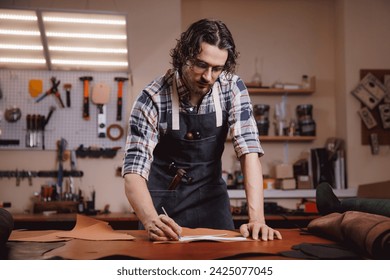 Cobbler Man tailor cuts out blanks for sewing bags or shoes according to pattern made of leather in workshop. - Powered by Shutterstock