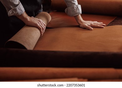 Cobbler working with natural brown leather, top view dark background. - Powered by Shutterstock