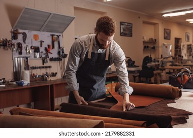 Cobbler working with skin textile in workshop. Tailor hold different rolls natural brown leather. - Powered by Shutterstock