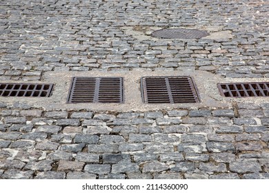 Cobblestone Granite Stone Road With Drain Grates For Stormwater Drainage Urban Streets Improvement In The Old European Town Close-up, Nobody.