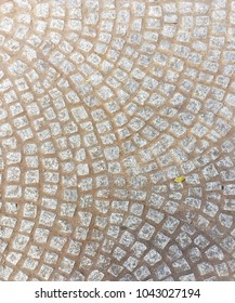 Cobblestone Path With Square Cobble Stones In A Concentric Circle Pattern With One Leaf On The Stones