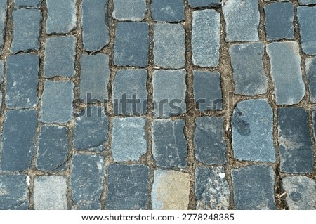 Cobblestone pavement texture top view. Ancient stone blocks of a city street road surface. Grey granite sett stones pattern for architectural background.