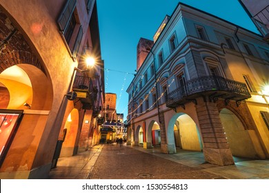 Cobblestone pedestrian street illuminated in evening in Old Town of Alba, Piedmont, Northern Italy (low angle view). - Powered by Shutterstock