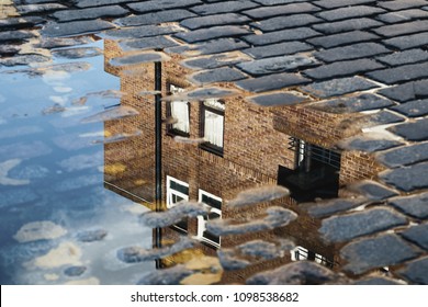 Cobblestone With Reflection Of House In Puddle After Rain