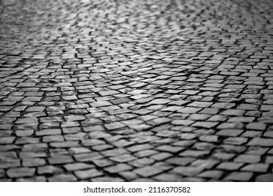 Cobblestone street in Iserlohn Sauerland Germany. Wheathered historic basalt ashlars or blocks in a lost place industrial area. Old pavement background with typical surface and structure, greyscale.