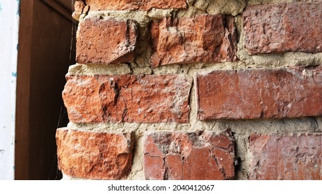 Cobweb-covered Chirp Corner Of A Street Wall Exposed To Time And Environment, Close-up Of The Edge Of A Brick Wall With Cracks And Chips In The Structure, Texture Of Shabby Brickwork In Detail