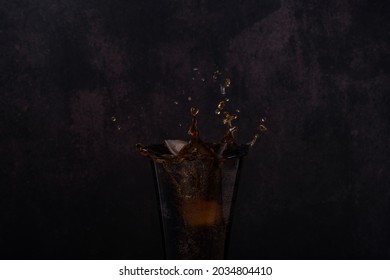 Coca Cola Coke Or Pepsi In Glass With Ice Drop And Water Splash In Dark Black Background.