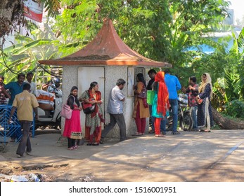 Cochin, India - January 4 2006 - A Group Of Indian People Queue Up At A Kiosk, Surrounded By Lush Vegetation.  Image Has Copy Space.