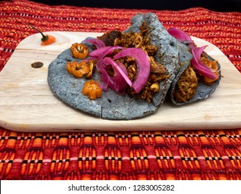 Cochinita pibil tacos, pork marinated in achiote sauce and blue corn tortilla