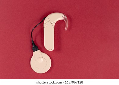 Cochlear Implant On A Red Background. Hearing Aid. MED-EL