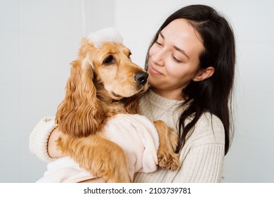 Cocker Spaniel Tacking A Bath With His Human In The Bath Tub. Woman Using A Towel To Comfort Her Pet