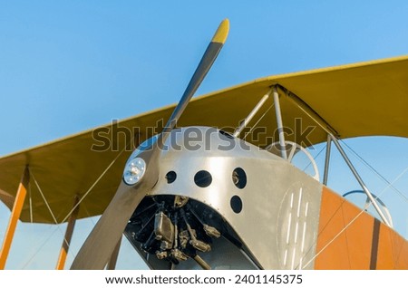 cockpit with an engine with a propeller and wings of a yellow vintage airplane against a blue sky close up in isolation