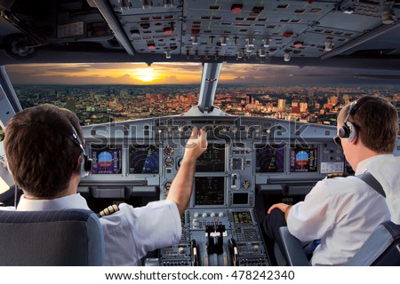 Cockpit view of modern airplane in flight during the sunset. Aircraft pilot at work.
