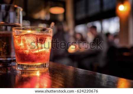 Cocktail close up in a bar setting. Blurred people in the background. Selective focus on the icy drink and glass.