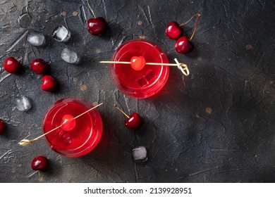 Cocktail Garnished With Cherry, Fresh Cranberry Juice With Ice On A Dark Background, Two Glasses, Top Shot With A Place For Text