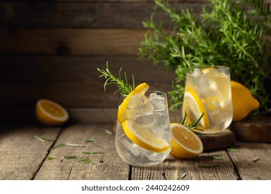 Cocktail gin tonic with ice, lemon, and rosemary on a old wooden table. Copy space. - Powered by Shutterstock