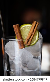 Cocktail Glass With Ice, A Slice Of Lime And A Cinnamon Stick, Ready To Be Filled By Professional Barman. Warm, Cozy Bar Atmosphere. Bokeh And Blurry Background.