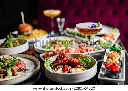cocktail glass on table full of delicious food in plates in restaurant
