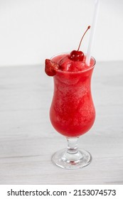 Cocktail Glass Of Red Frozen Strawberry Daiquiri With Cherry On Top Against Plain Background